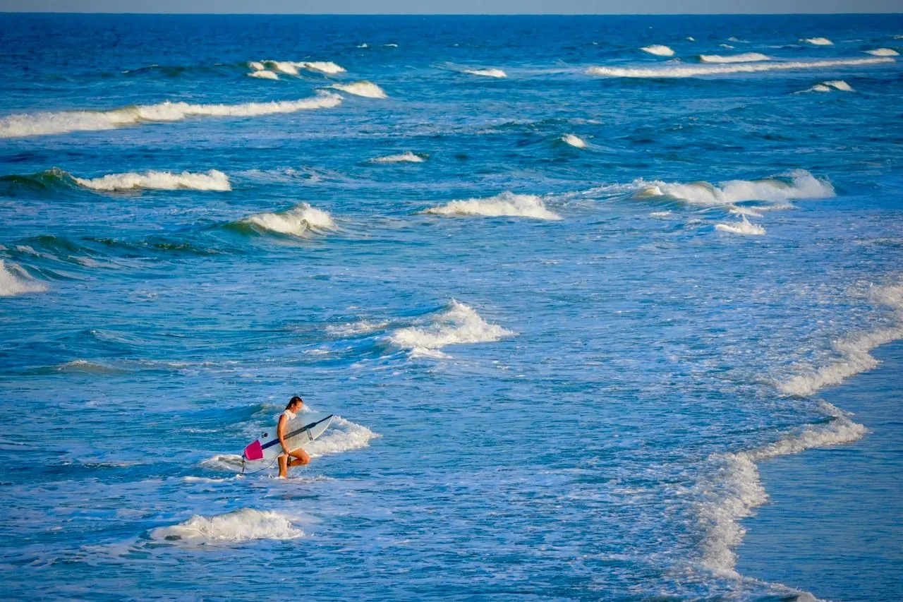 A paddleboarder heading out through the waves