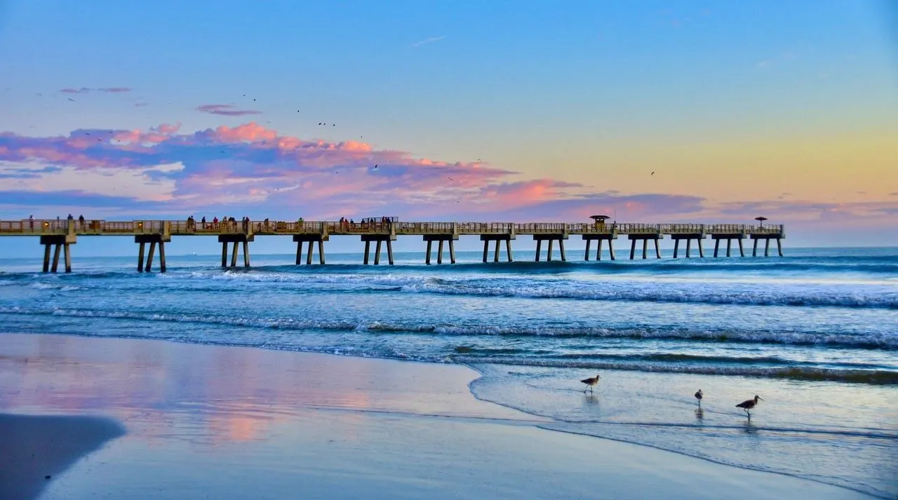 Pier at sunrise, with seagulls on the shore